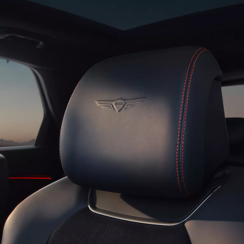 Interior close-up of Genesis logo stitched into Ultra Marine Blue headrest inside Genesis GV70