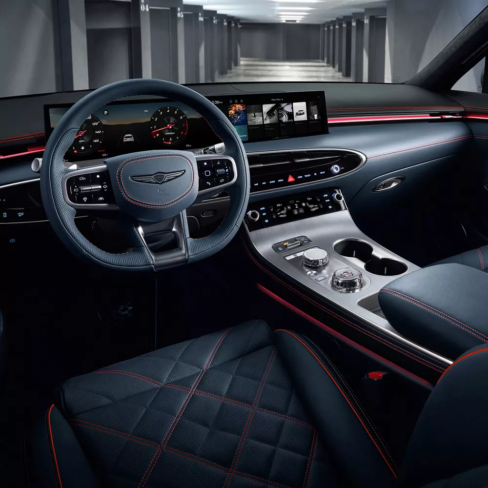 Interior driver seat pov of Genesis GV70 cockpit in Ultramarine Blue Nappa leather, orange stitching