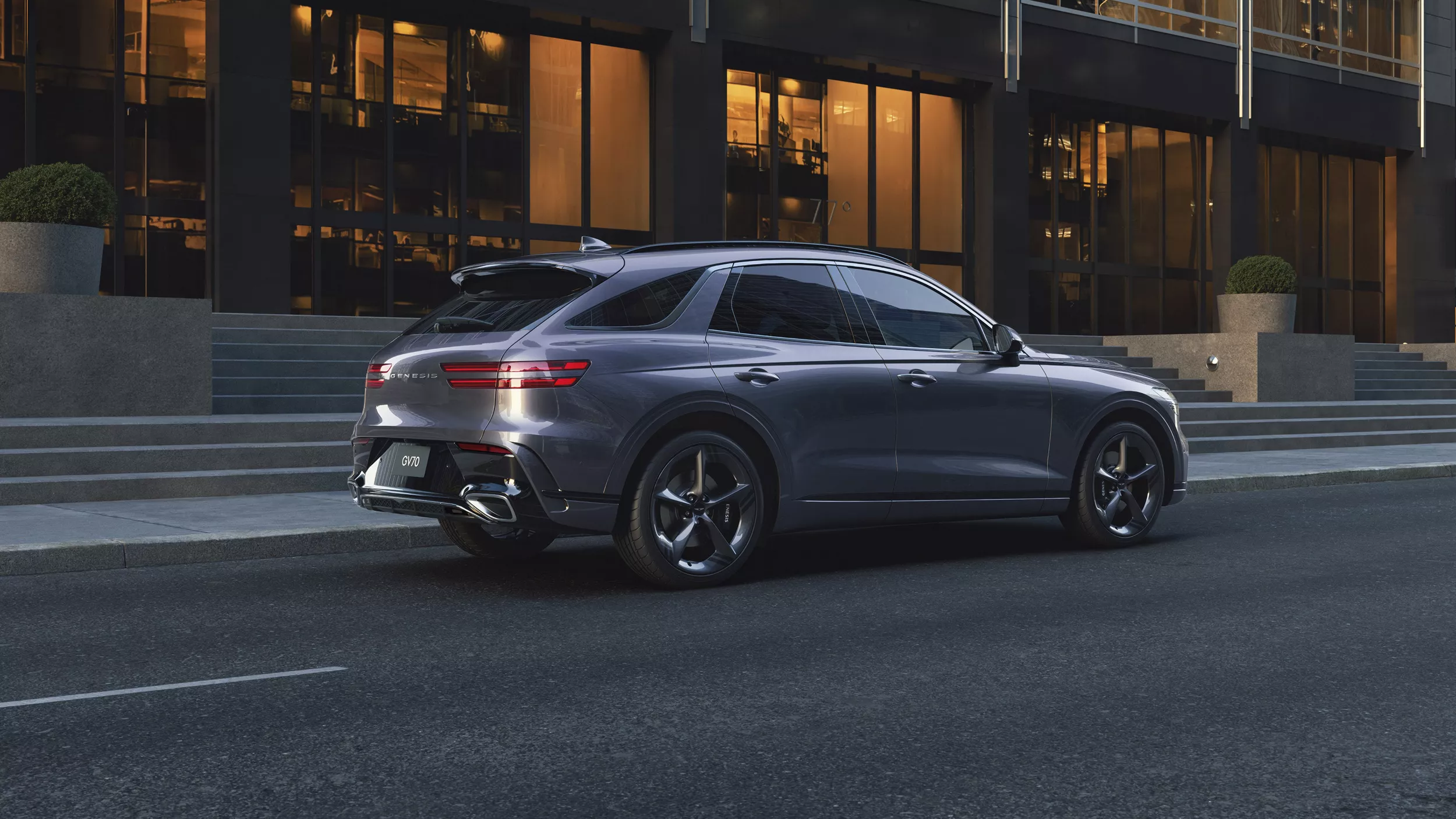 7/8 rear passenger side view of Genesis GV70 in Ceres Blue, driving along city street