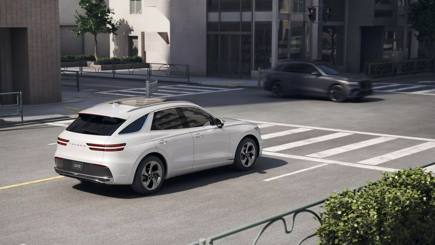 3/4 rear passenger side view of white Genesis GV70 at city crosswalk, gray GV70 passes perpendicular