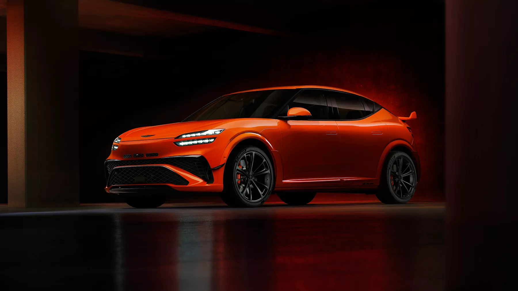 3/4 front driver side view of 2027 Genesis GV60 Magma in orange, parked in dimly lit garage