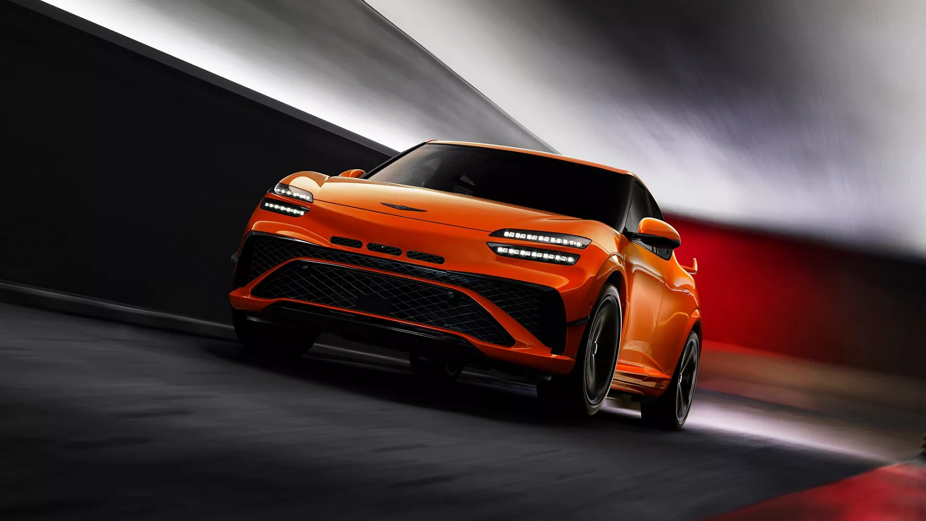 3/4 front driver side view of 2027 Genesis GV60 Magma in orange driving through tunnel