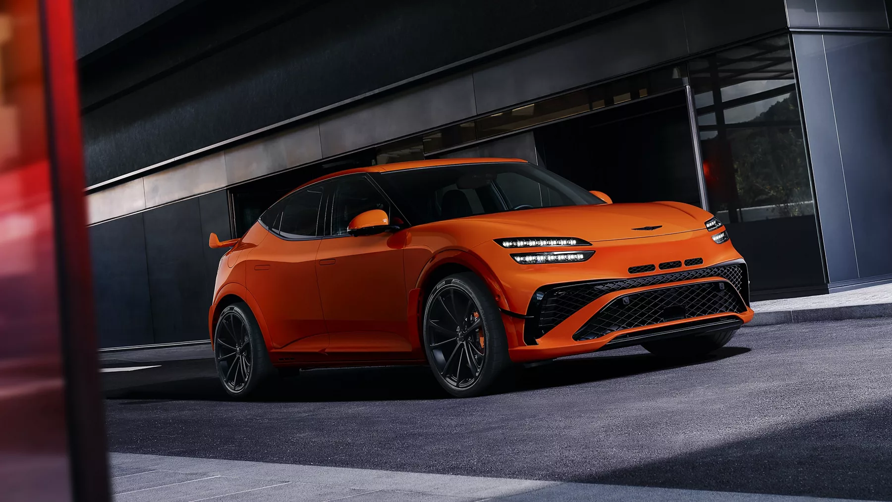 3/4 passenger side view of 2027 Genesis GV60 Magma in orange