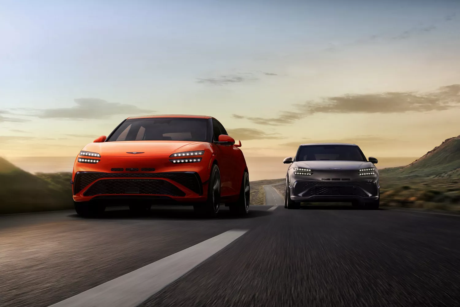 2027 Genesis GV60 Magma vehicles in orange and gray driving narrow mountain road
