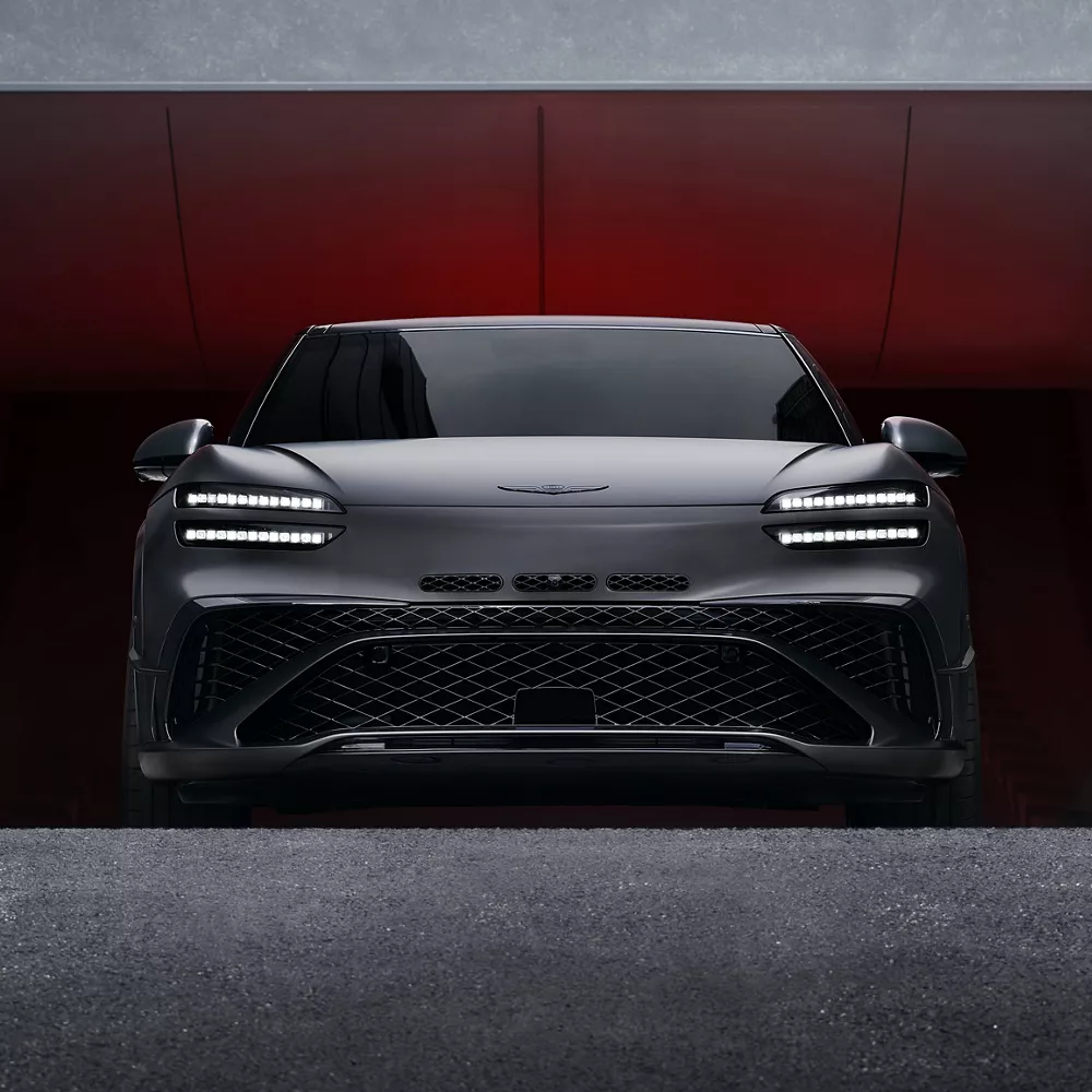 Close up front angle of Genesis 2027 GV60 Magma driving up from a parking ramp