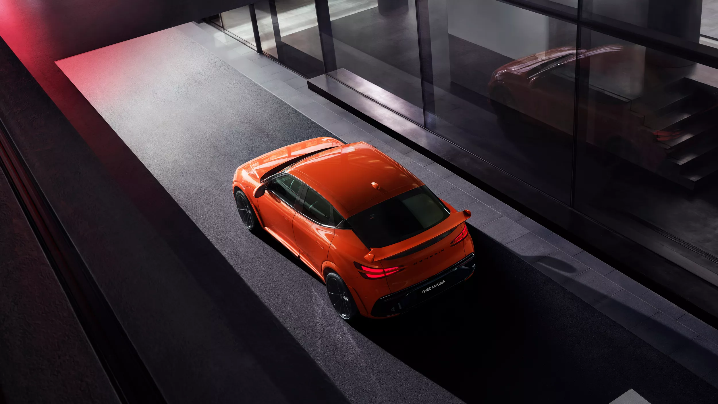 Aerial 3/4 rear driver side view of 2027 Genesis GV60 Magma in orange