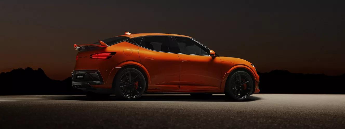 Passenger profile view of 2027 Genesis GV60 Magma in orange parked, with mountains in back at night