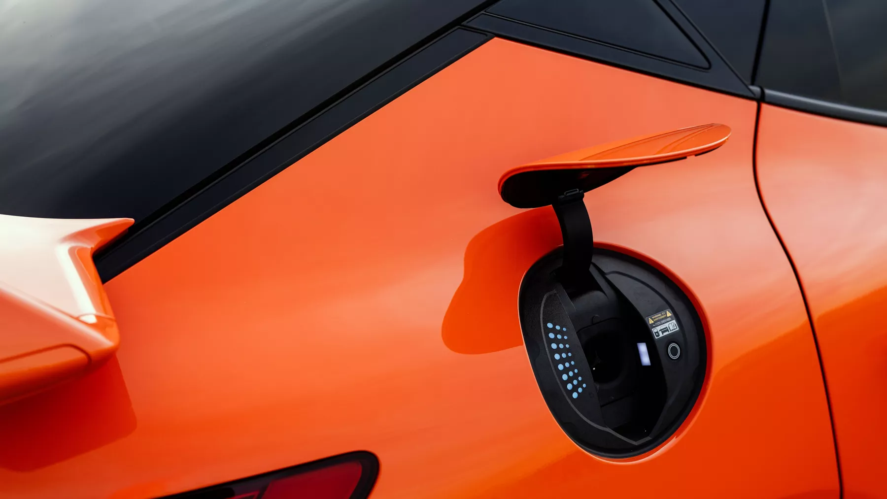 Close up of charging port on rear passenger side of 2027 Genesis GV60 Magma in orange