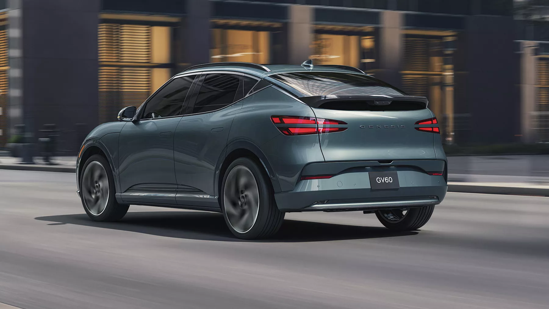 3/4 rear driver side view of Genesis GV60 in Tromso Green driving through city streets