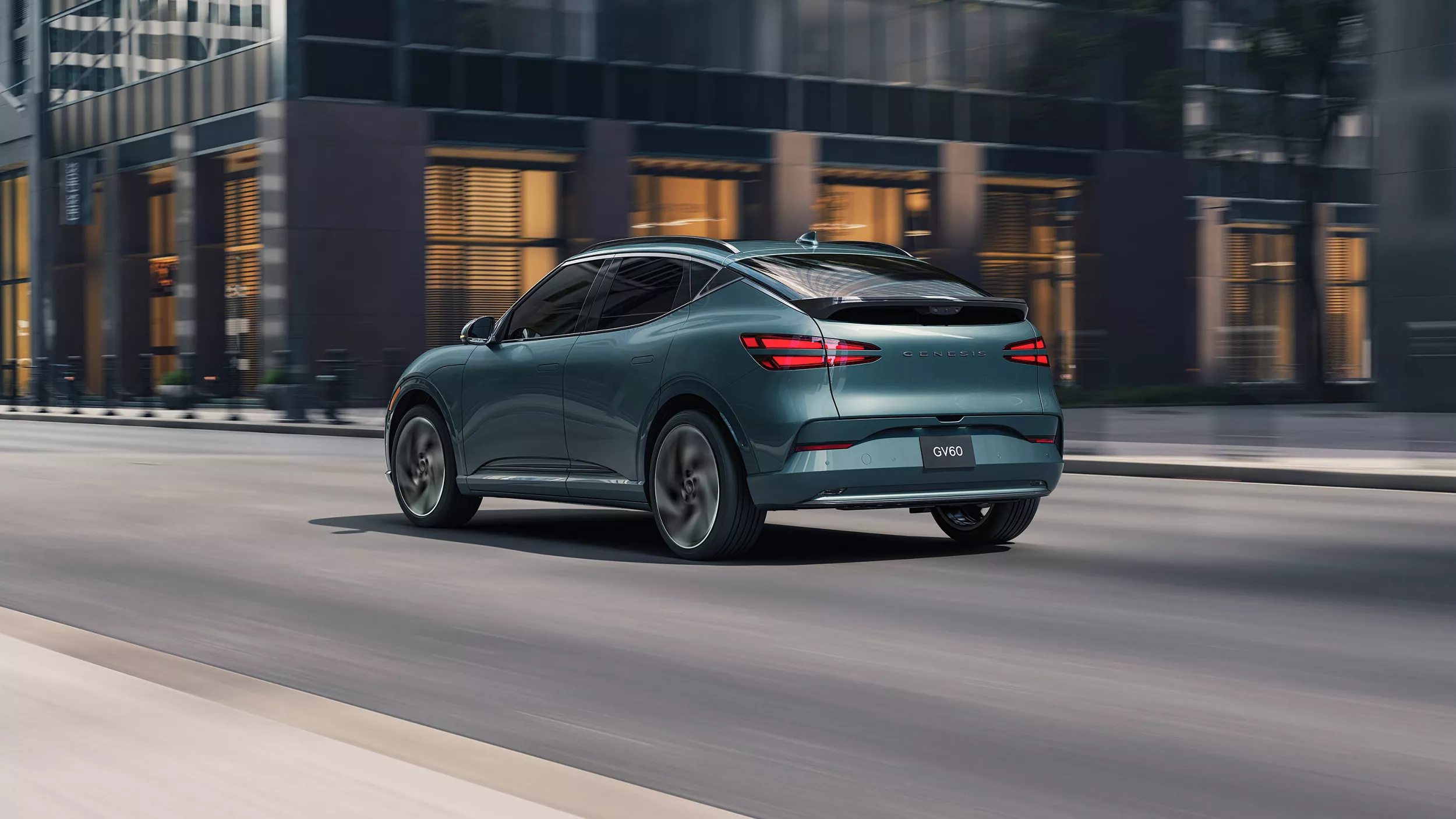 3/4 rear driver side view of Genesis GV60 in Tromso Green driving through city streets