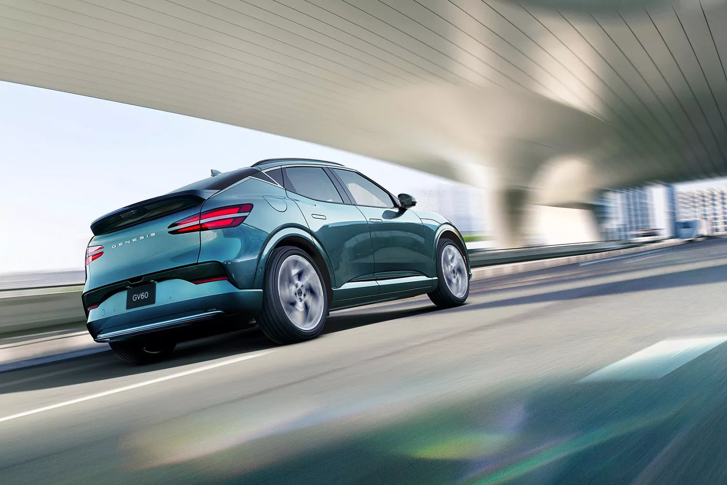 3/4 rear passenger side view of Genesis GV60 in Tromso Green, diving under futuristic bridge in city