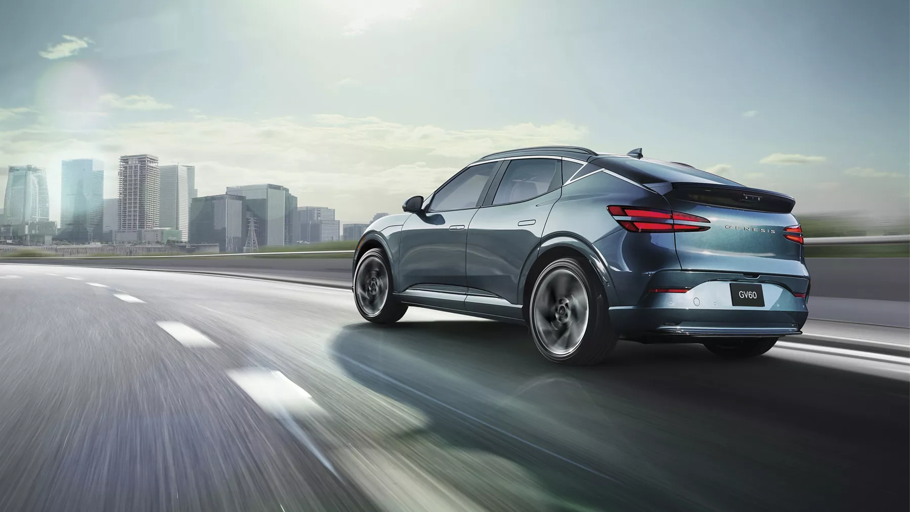 3/4 rear driver side view of Genesis GV60 in Tromso Green on highway, approaching city skyline