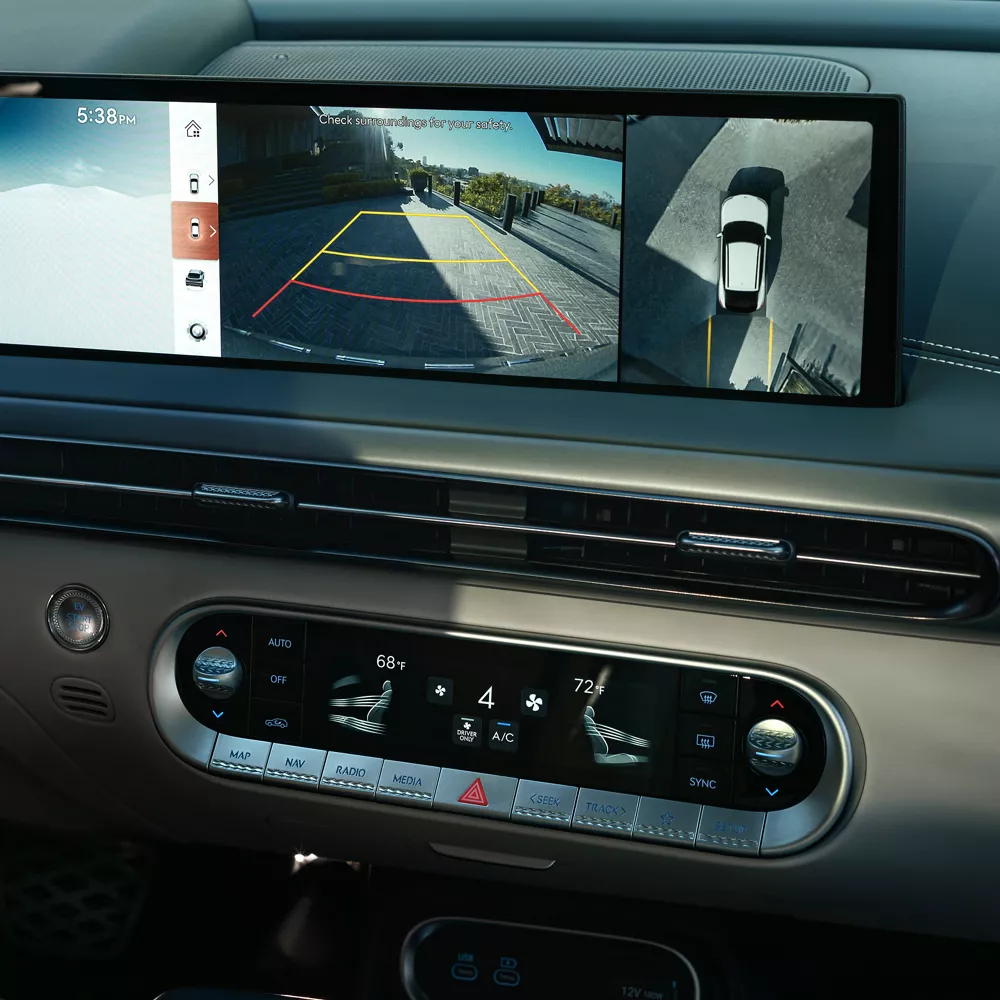 Interior close up of hand on steering wheel, rear/overhead cameras on dashboard, inside Genesis GV60