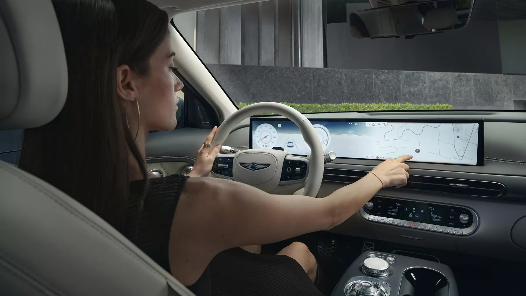 Interior view from backseat of driver touching infotainment display inside Genesis GV60