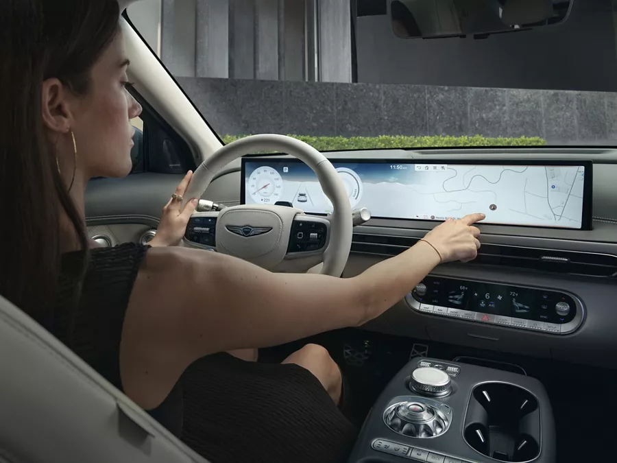 Interior view from backseat of driver touching infotainment display inside Genesis GV60