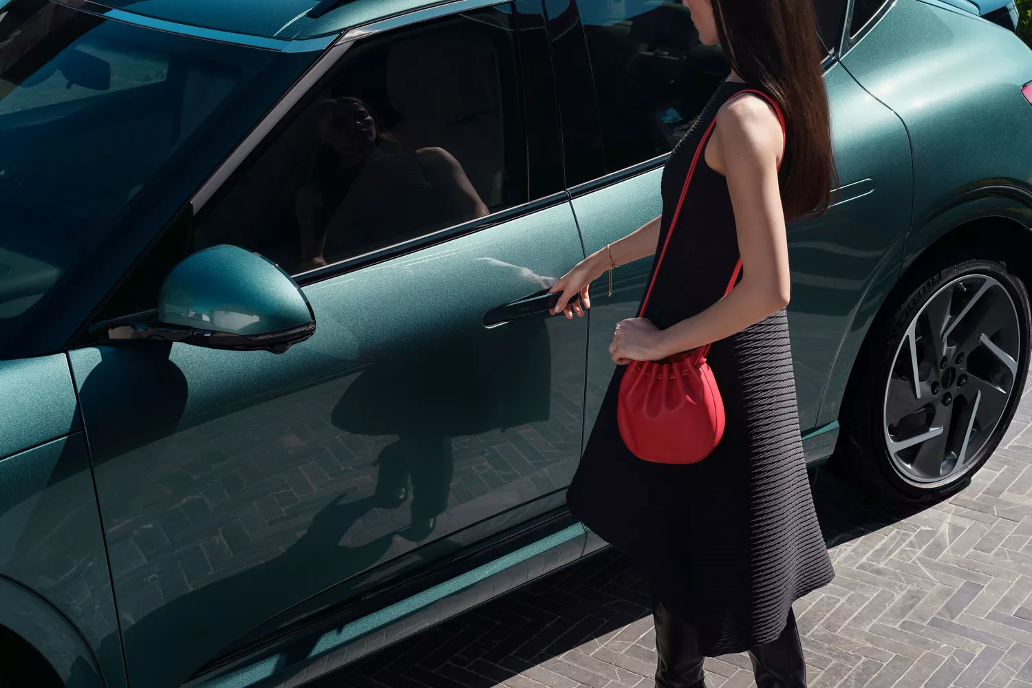 3/4 aerial driver side close up of woman opening door on Genesis GV60 in Tromso Green