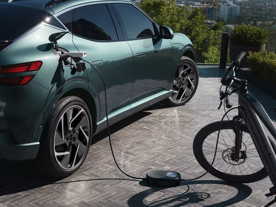 3/4 rear passenger side view of eBike connected to Genesis GV60 (in Tromso Green) via charging port