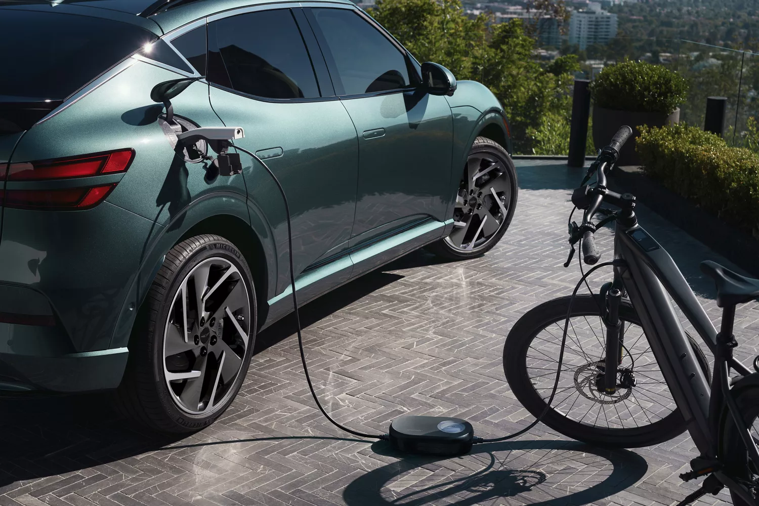 3/4 rear passenger side view of eBike connected to Genesis GV60 (in Tromso Green) via charging port