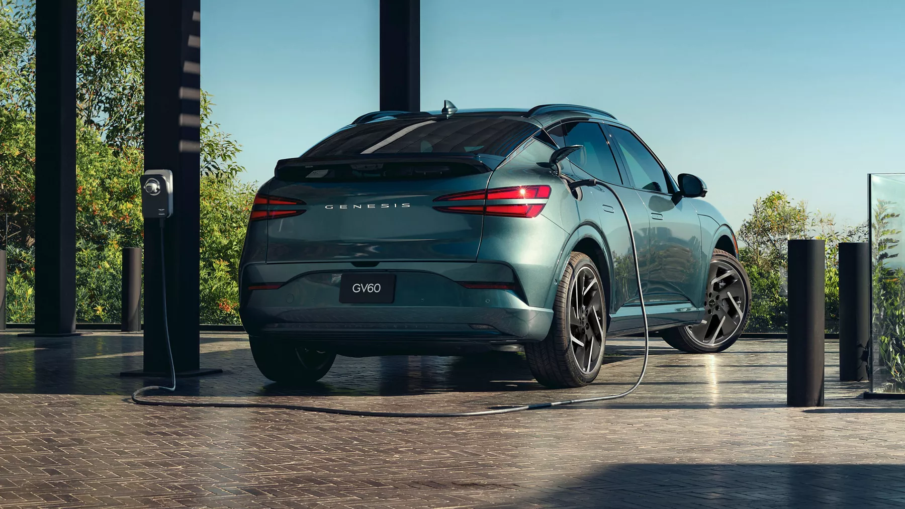 3/4 rear passenger side view of Genesis GV60 in Tromso Green, connected to charging station