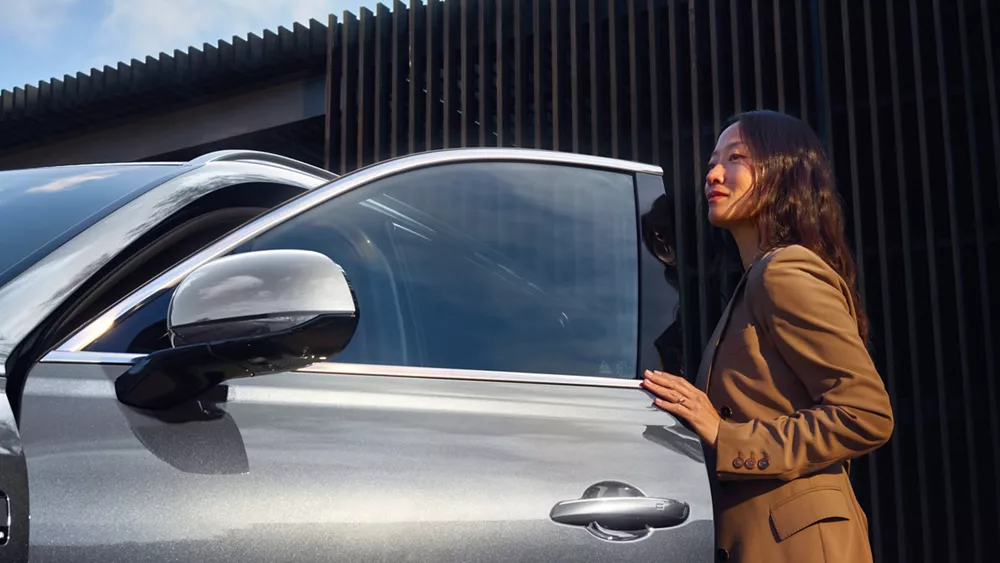 Closeup of woman opening driver side door of Genesis GV80 in Savile Silver