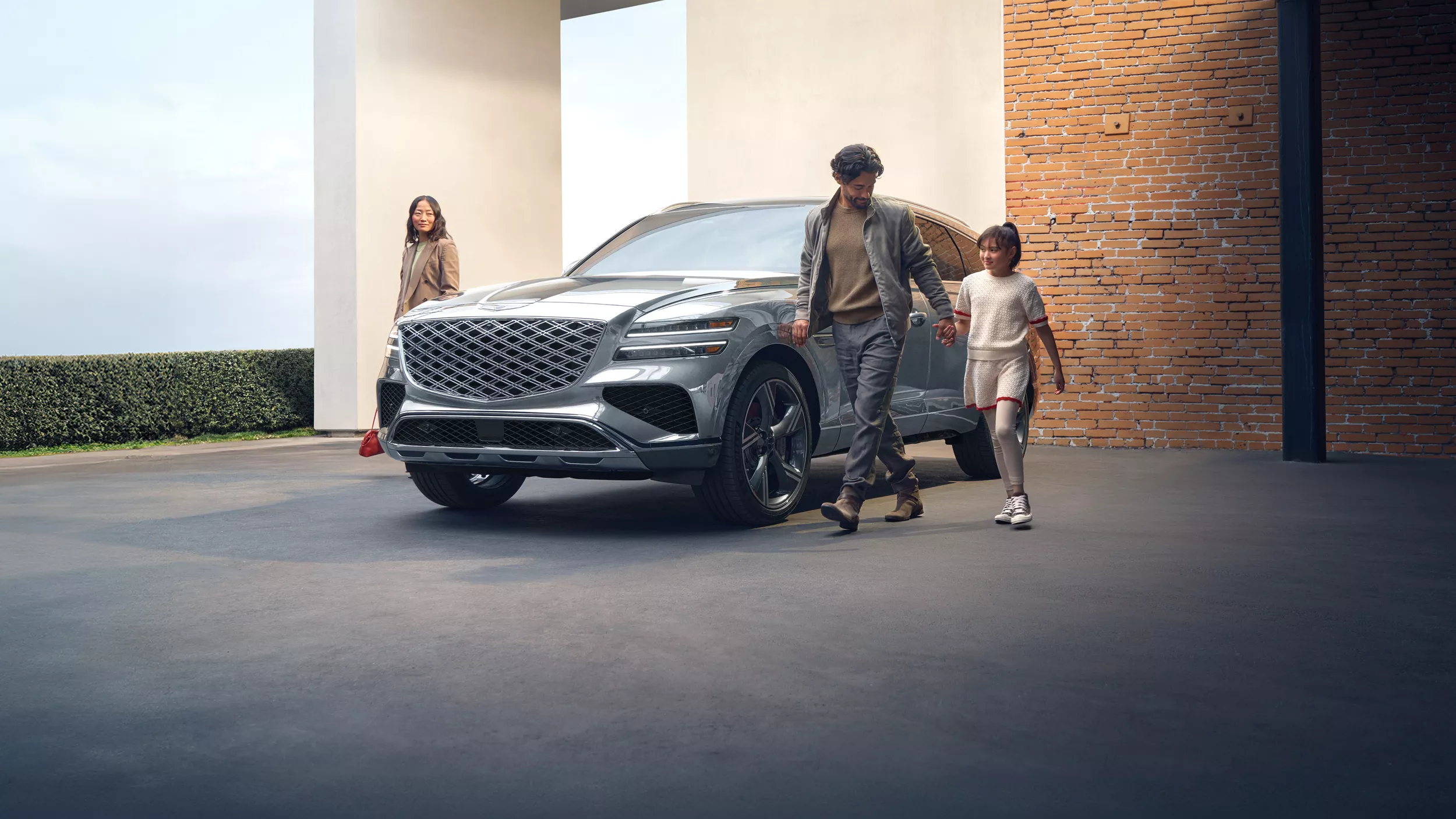 3/4 front driver side view of family walking around Genesis GV80