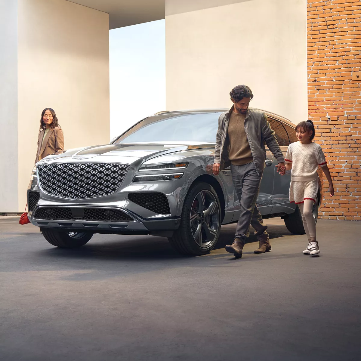 3/4 front diver side view of Genesis GV80 in Savile Silver, family walking alongside