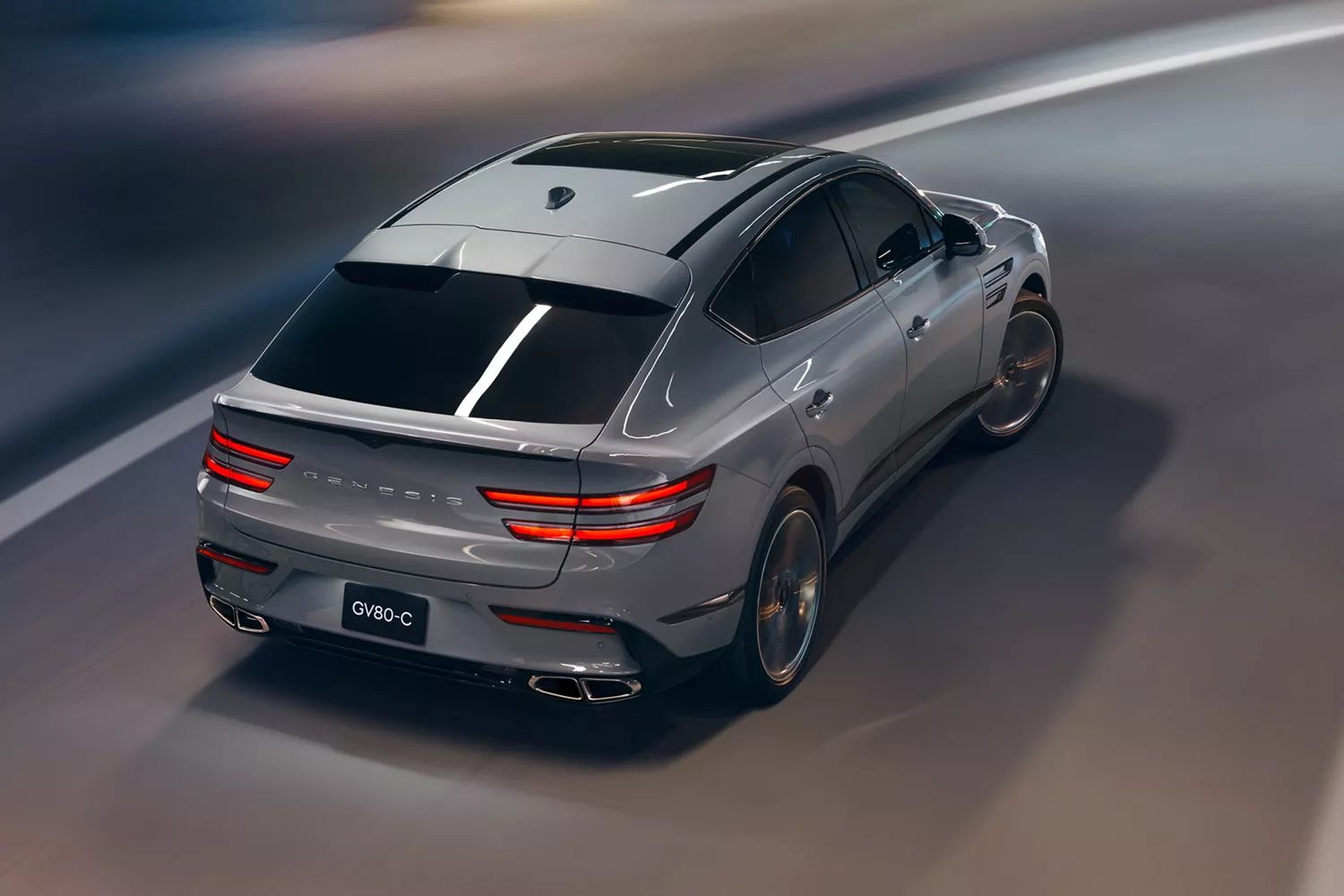 Rear overhead action shot of Genesis GV80 Coupe in Bering Blue driving through a parking structure