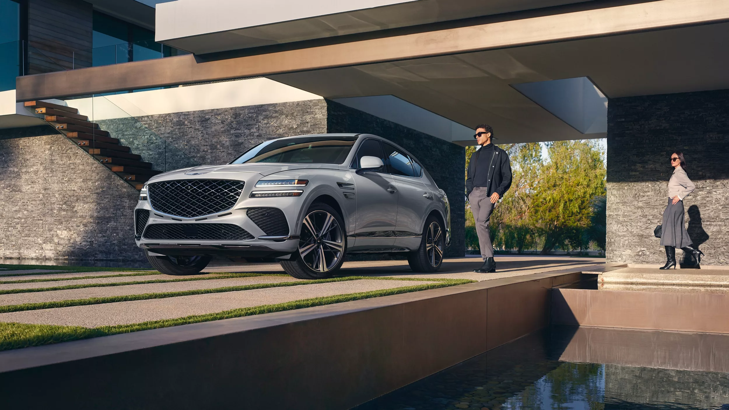 3/4 front driver side view of Genesis GV80 Coupe in Bering Blue parked in carport of modern home
