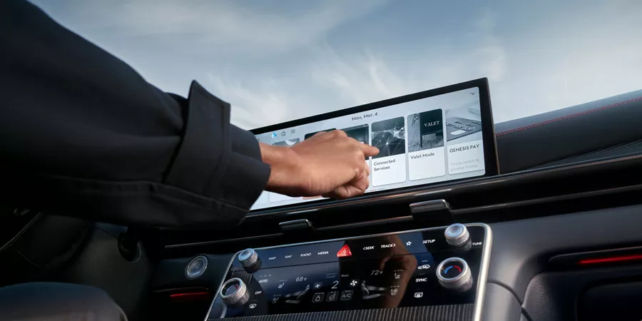 Interior closeup view of driver touching Navigation Integrated display inside Genesis GV80 Coupe