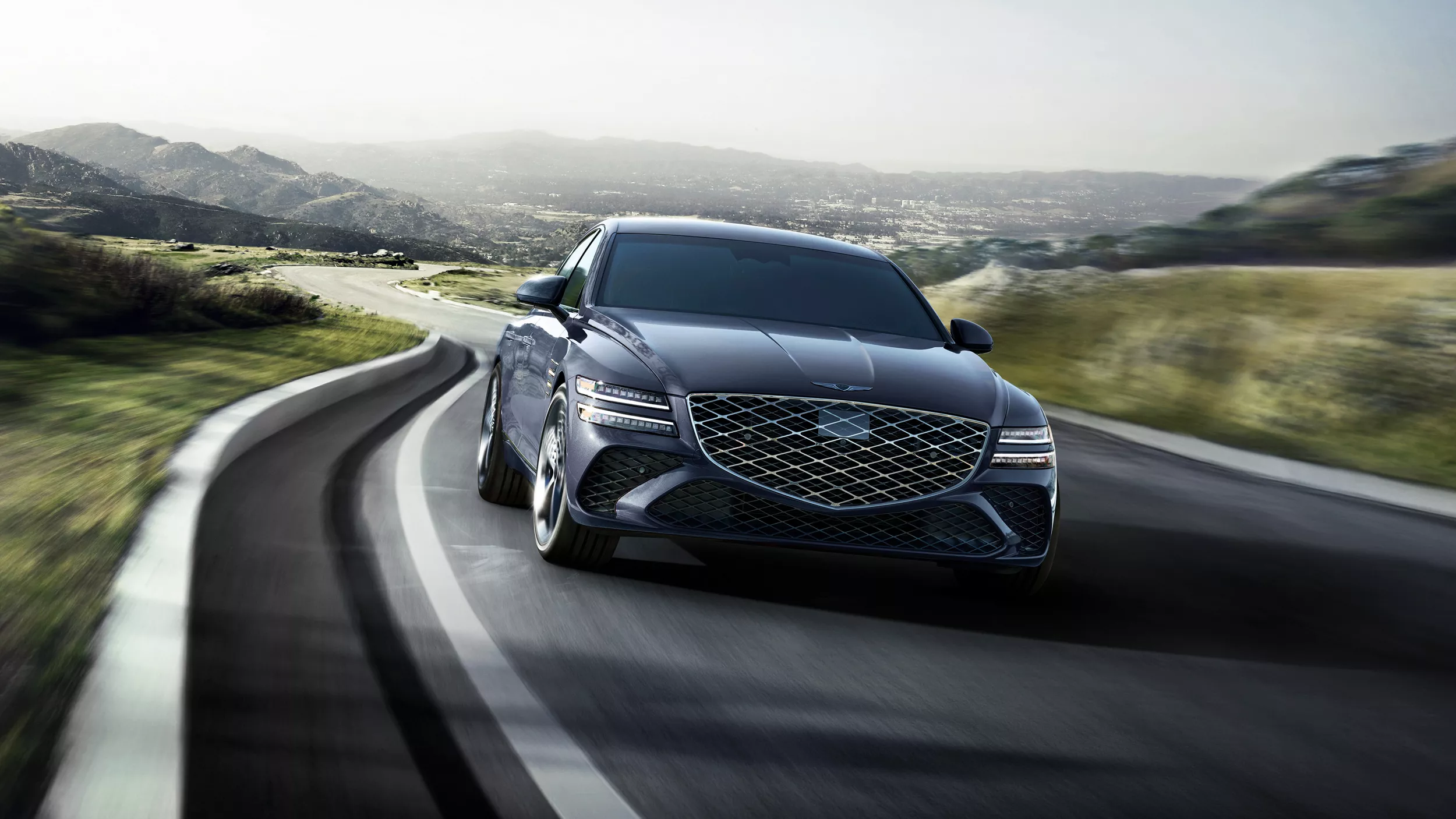 7/8 front passenger view of Genesis G80 in Ceres Blue driving country road with rolling hills