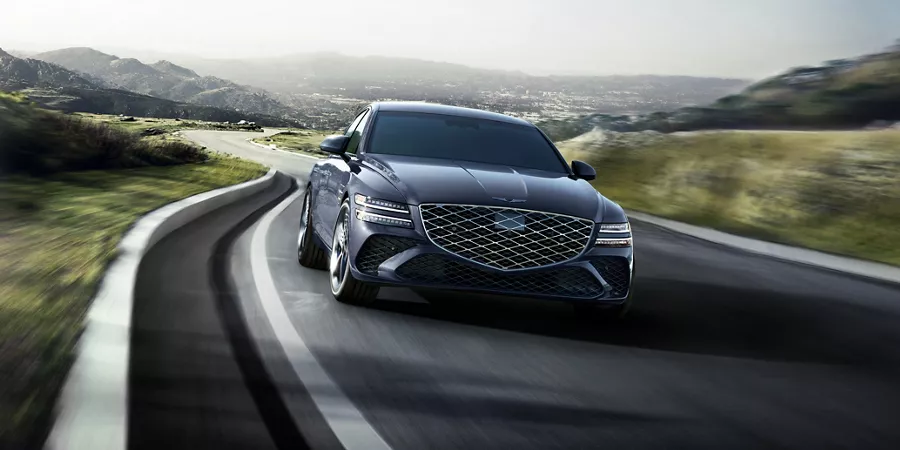 7/8 front passenger view of Genesis G80 in Ceres Blue driving country road with rolling hills