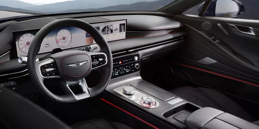 Driver side window pov looking into cockpit of Genesis G80 with mountains visible though windshield
