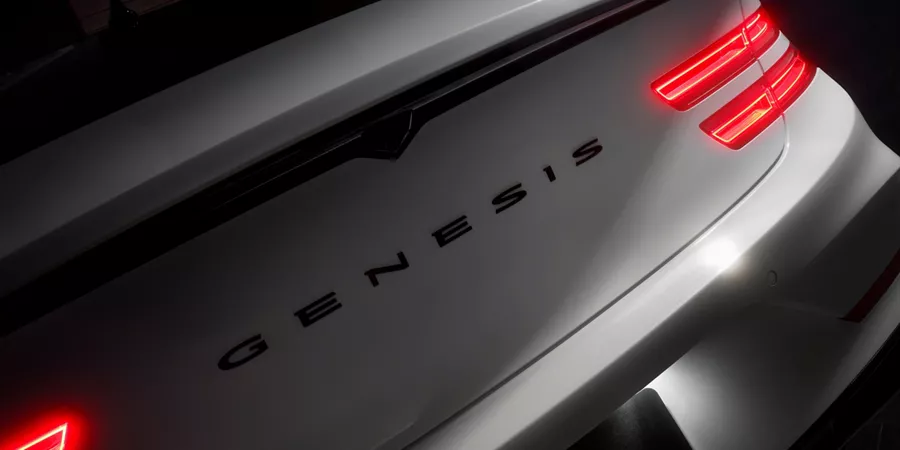 Rear view of Genesis G80 Prestige Black in Uyuni White with lit taillights, G80 on license plate