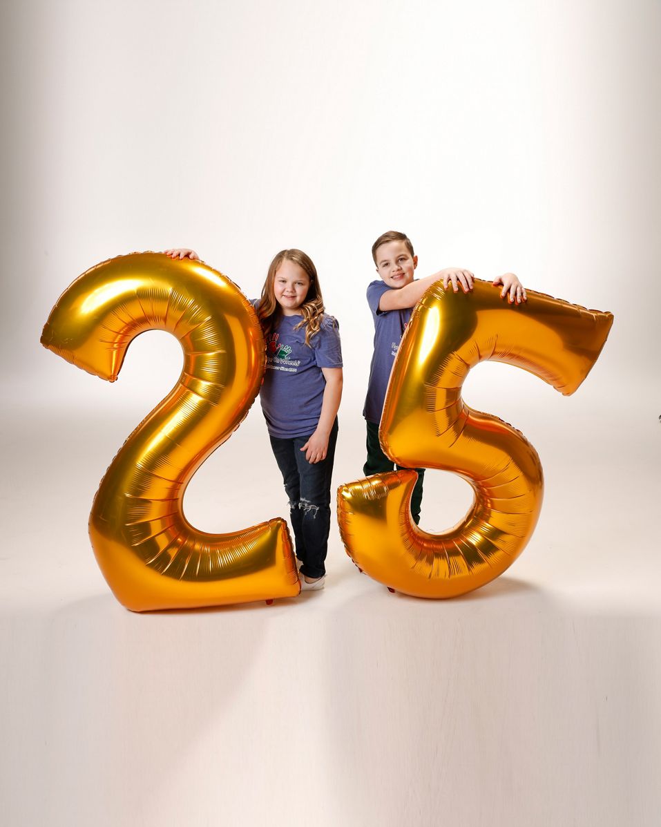 Raynie y Oliver con globos con el número 25