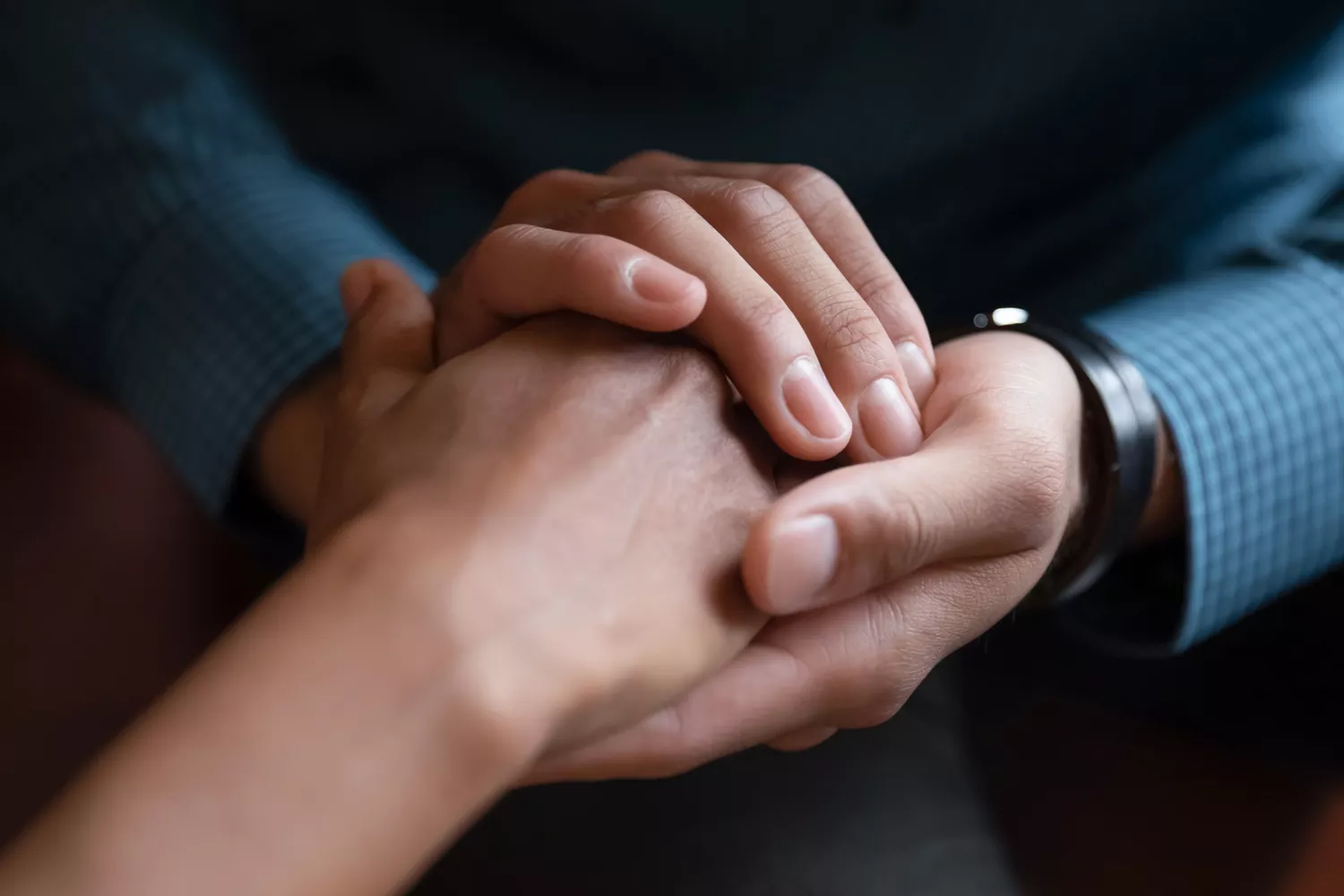 Close up image of two people holding hands comforting each other.
