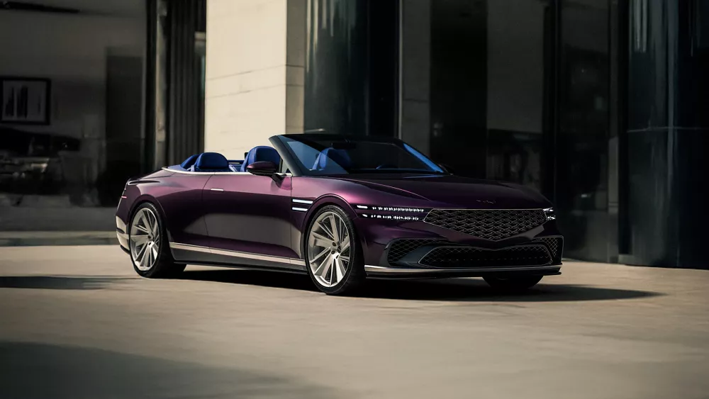 Passenger side 3/4 view of burgundy Genesis X Gran Convertible Concept in front of modern home