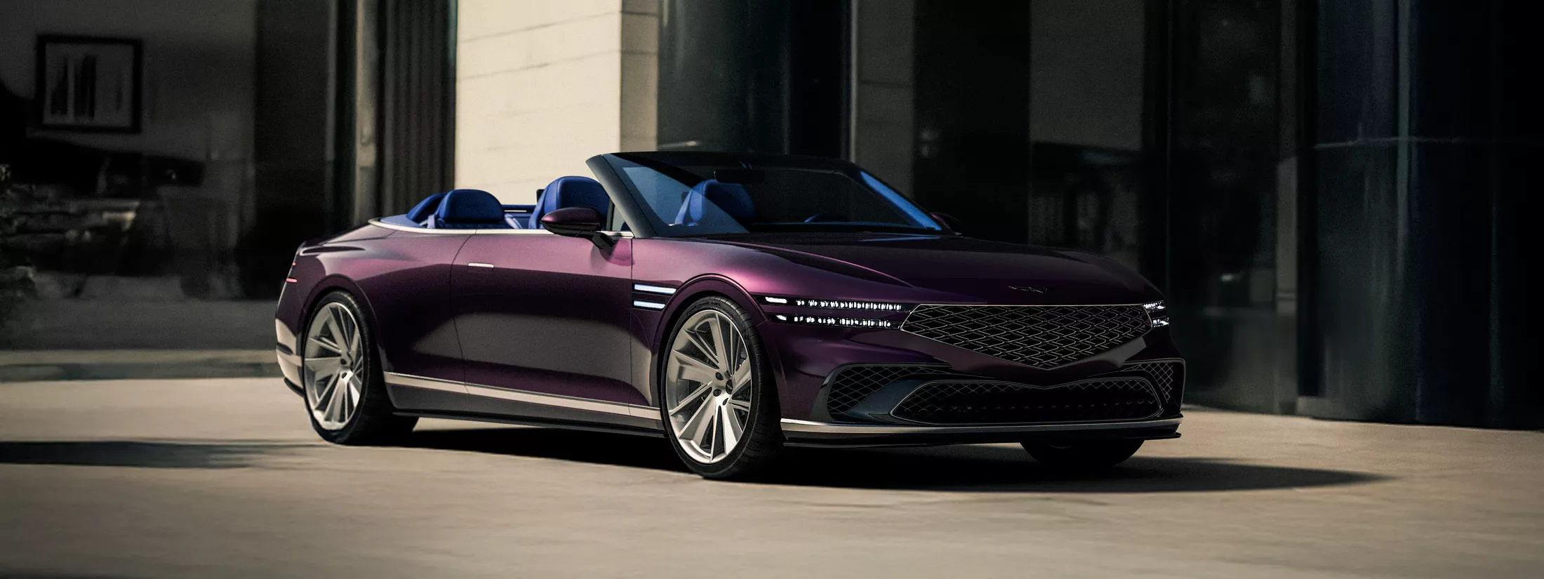 Passenger side 3/4 view of burgundy Genesis X Gran Convertible Concept in front of modern home