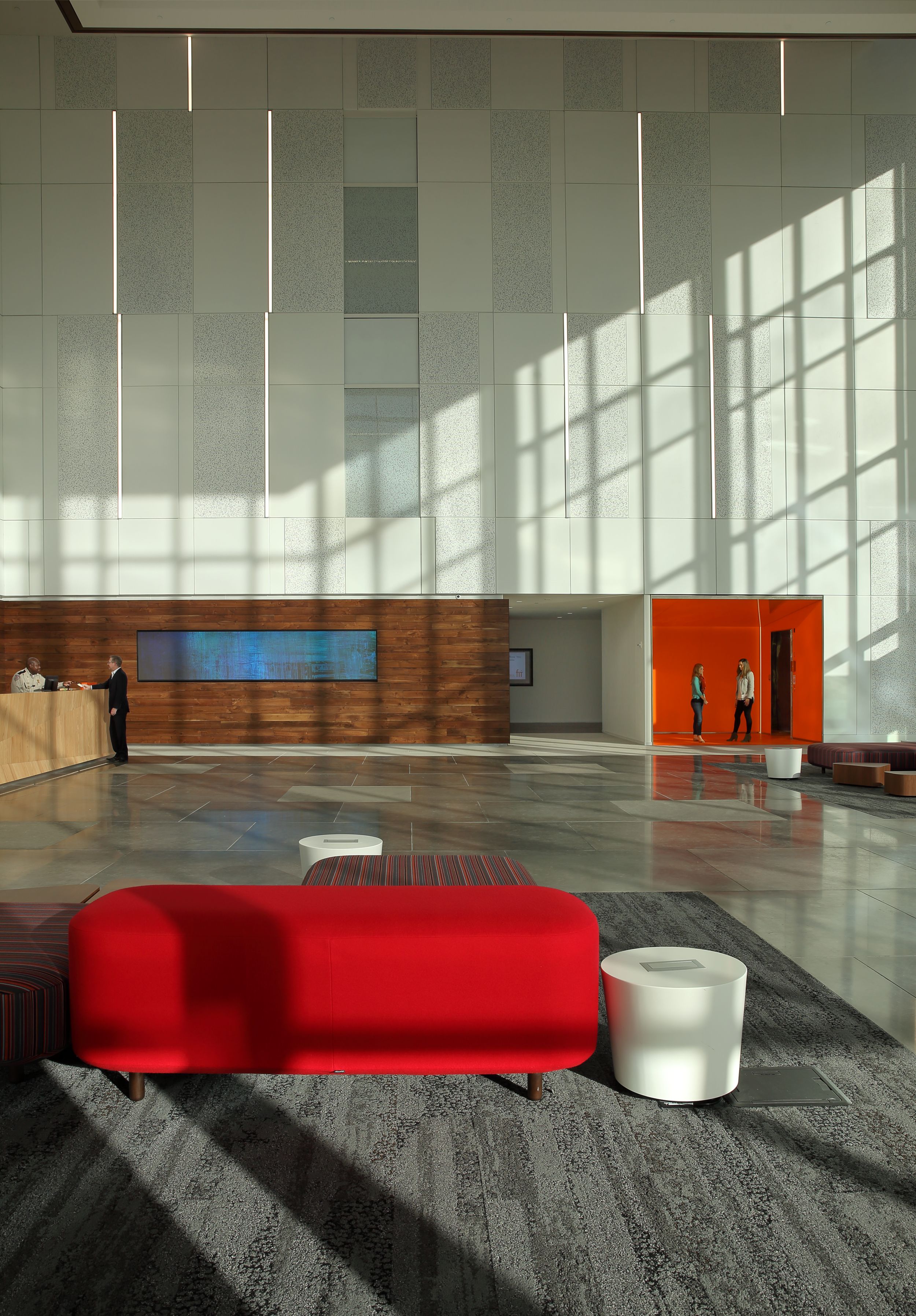 Interface HN850 plank carpet tile in open foyer with small wood wall and women talking in red room imagen número 12