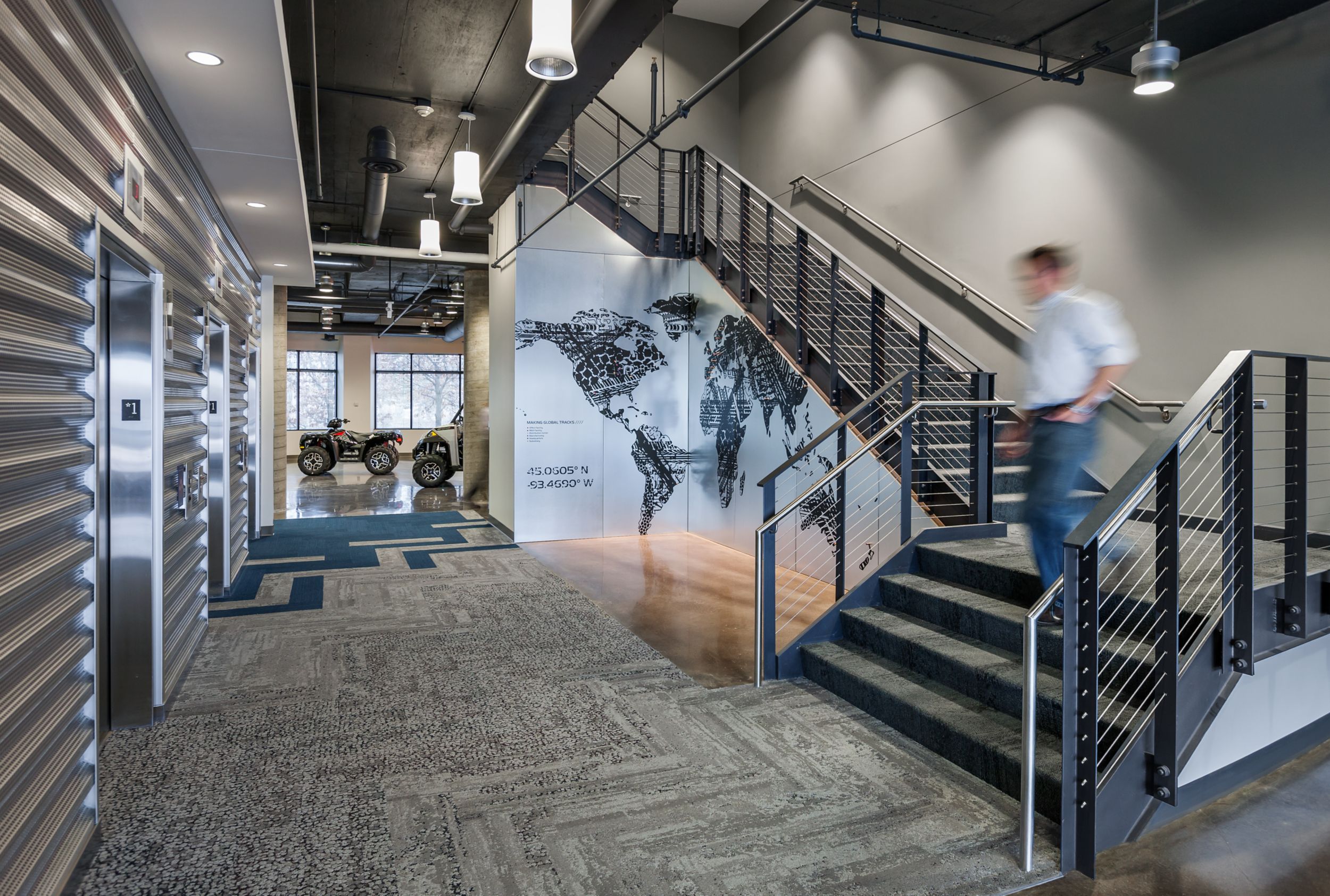 Interface HN810, HN820, HN840 and HN850 plank carpet tiles in open stairwell with four wheelers in background at Polaris Industries image number 10