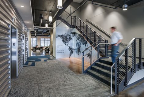 Interface HN810, HN820, HN840 and HN850 plank carpet tiles in open stairwell with four wheelers in background at Polaris Industries image number 6