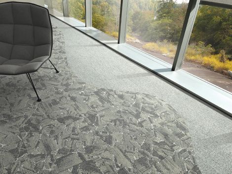 Interface Mile Rock carpet tile and Rockland Road plank carpet tile in close up with grey chair