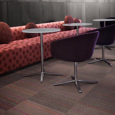 Interface 2nd Avenue carpet tile in lounge with long pink sofa, round tables and purple chairs imagen número 1