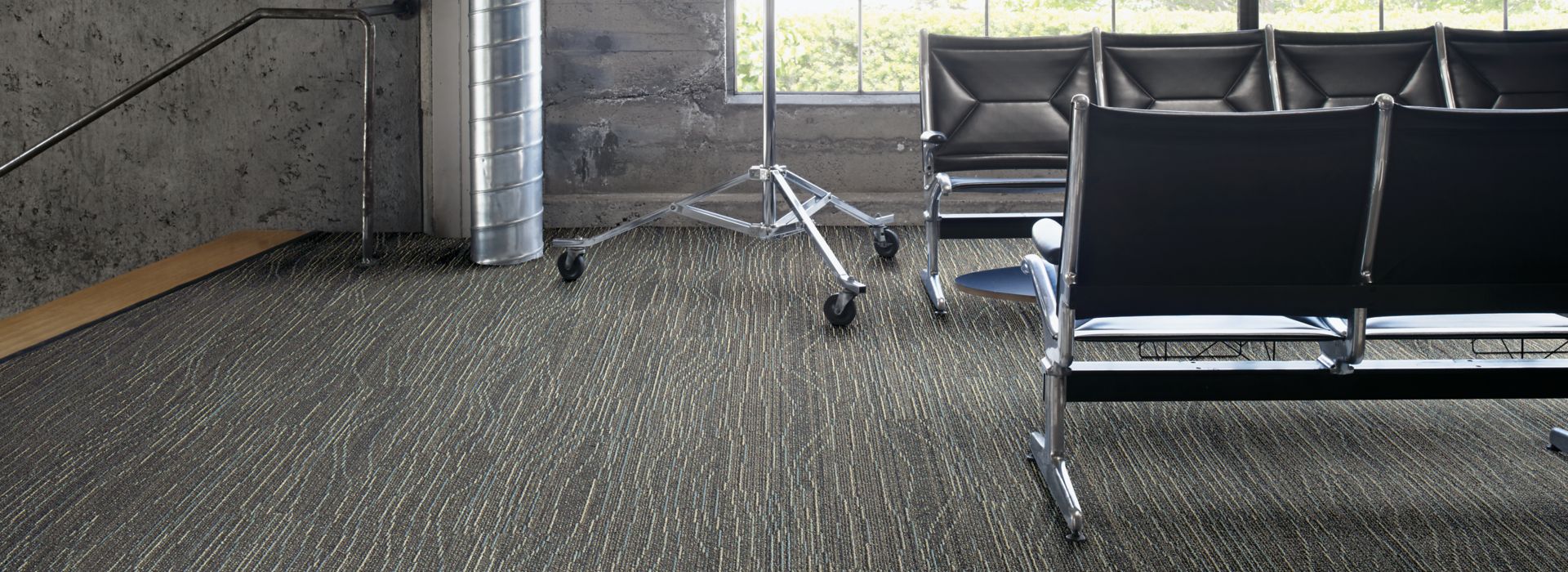 Interface Snow Moon plank carpet tile in waiting area with concrete walls and exposed beams