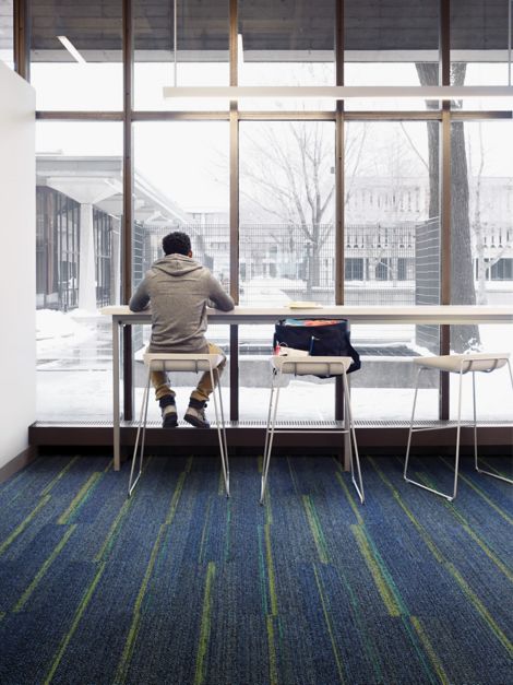 Interface Ground Waves plank carpet tiles in open area with student seated on stool image number 15