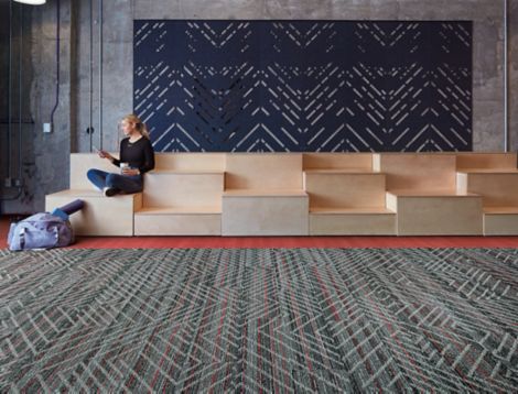 Interface Reflectors plank carpet tile with Studio Set LVT in open area with woman seated on wood risers