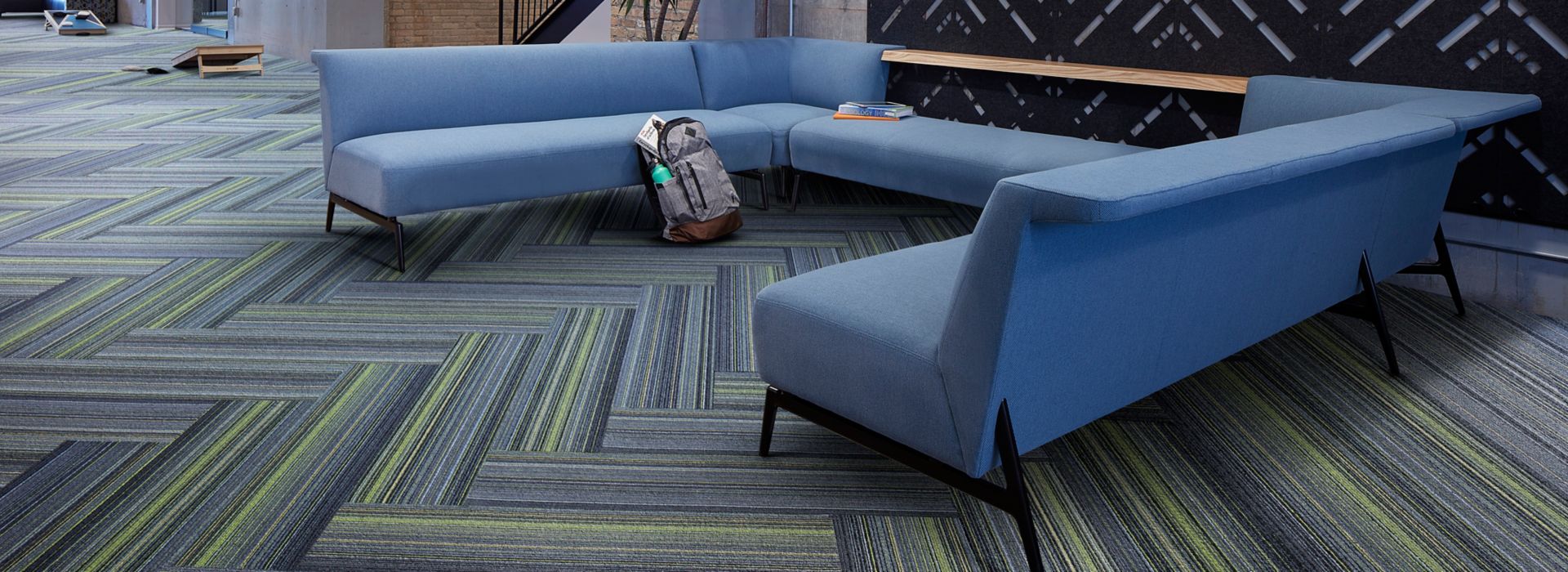 Interface Aglow and Reflectors plank carpet tile in lobby area with blue sectional