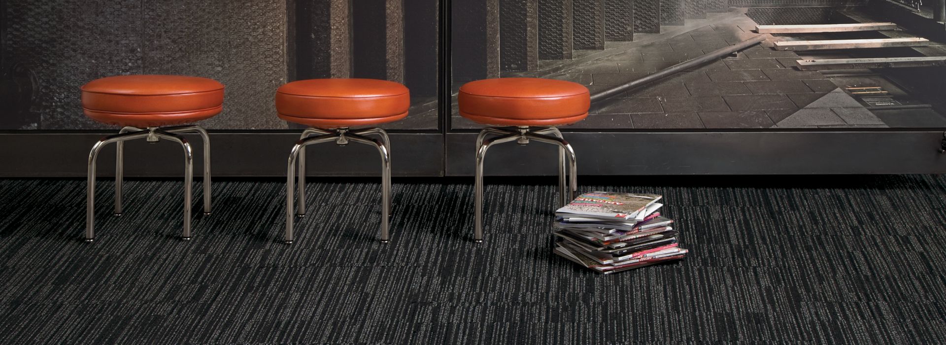 Interface CT102 carpet tile in open area with three red stools and stack of books imagen número 1