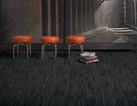 Interface CT102 carpet tile in open area with three red stools and stack of books