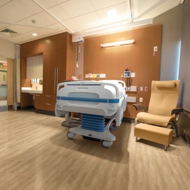 Interface Criterion Classic Woodgrains LVT in patient room with hospital bed and chair imagen número 1