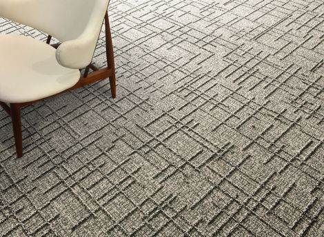 Detail of Interface DL925 carpet tile with cream colored chair